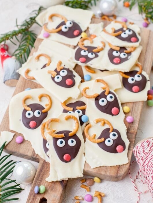 Christmas chocolate bark broken up into pieces on a wooden board.