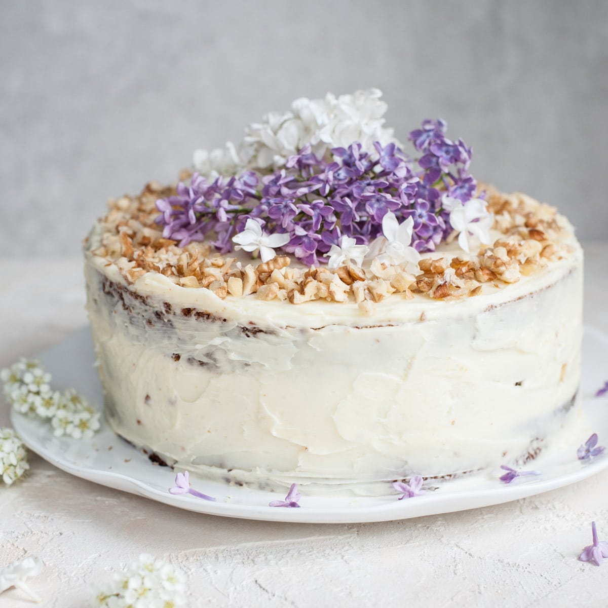Carrot layer cake topped with walnut and fresh flowers.