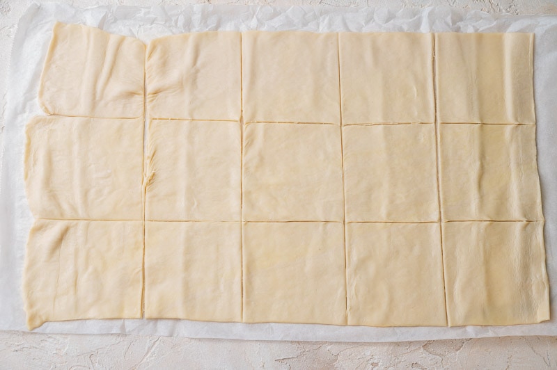 Rolled out puff pastry sheet cut into squares.