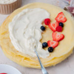A stack of crepes with cream cheese filling and berries on top.