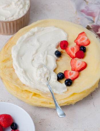 A stack of crepes with cream cheese filling and berries on top.