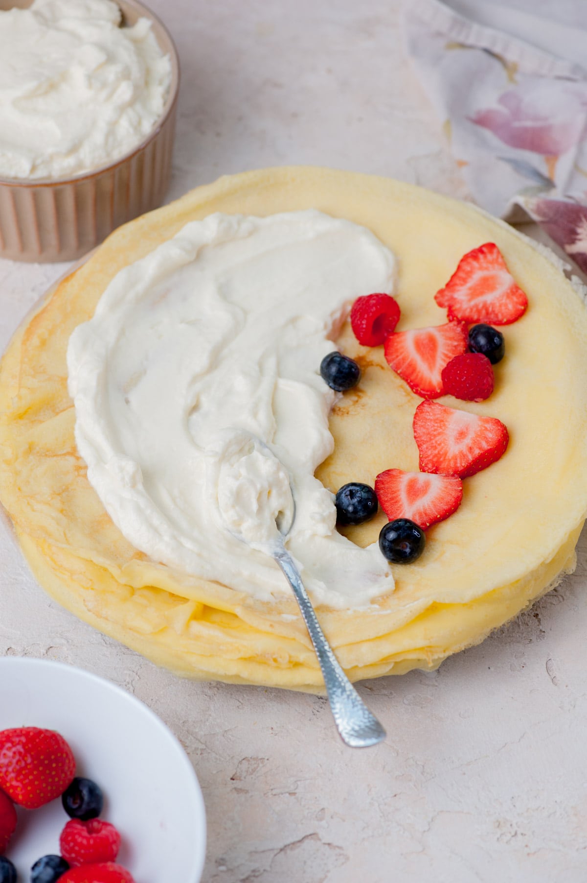 A stack of crepes with cream cheese filling on top and fresh berries.