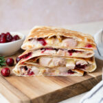 A stack of turkey quesadillas on a wooden board.