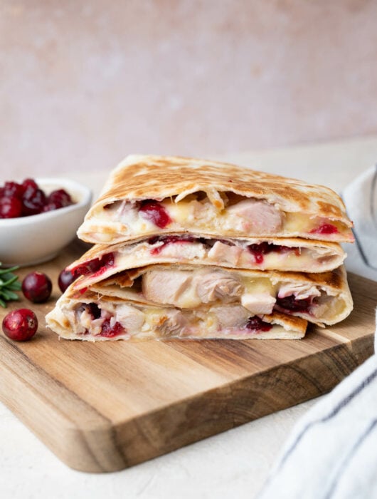 A stack of turkey quesadillas on a wooden board.