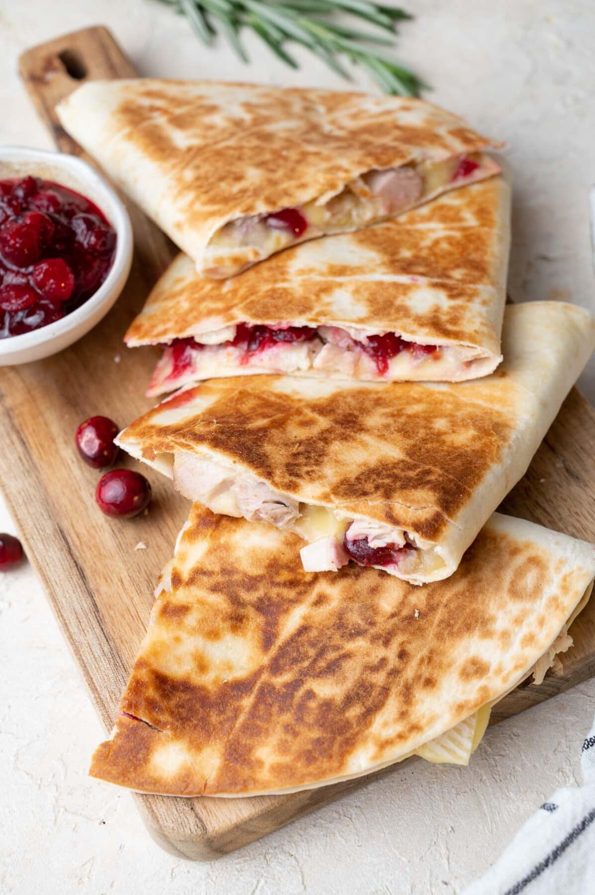 Turkey quesadillas with brie and cranberry sauce on a wooden board.