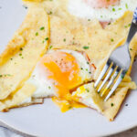 Savory crepes with cheese, egg, and ham on a plate.