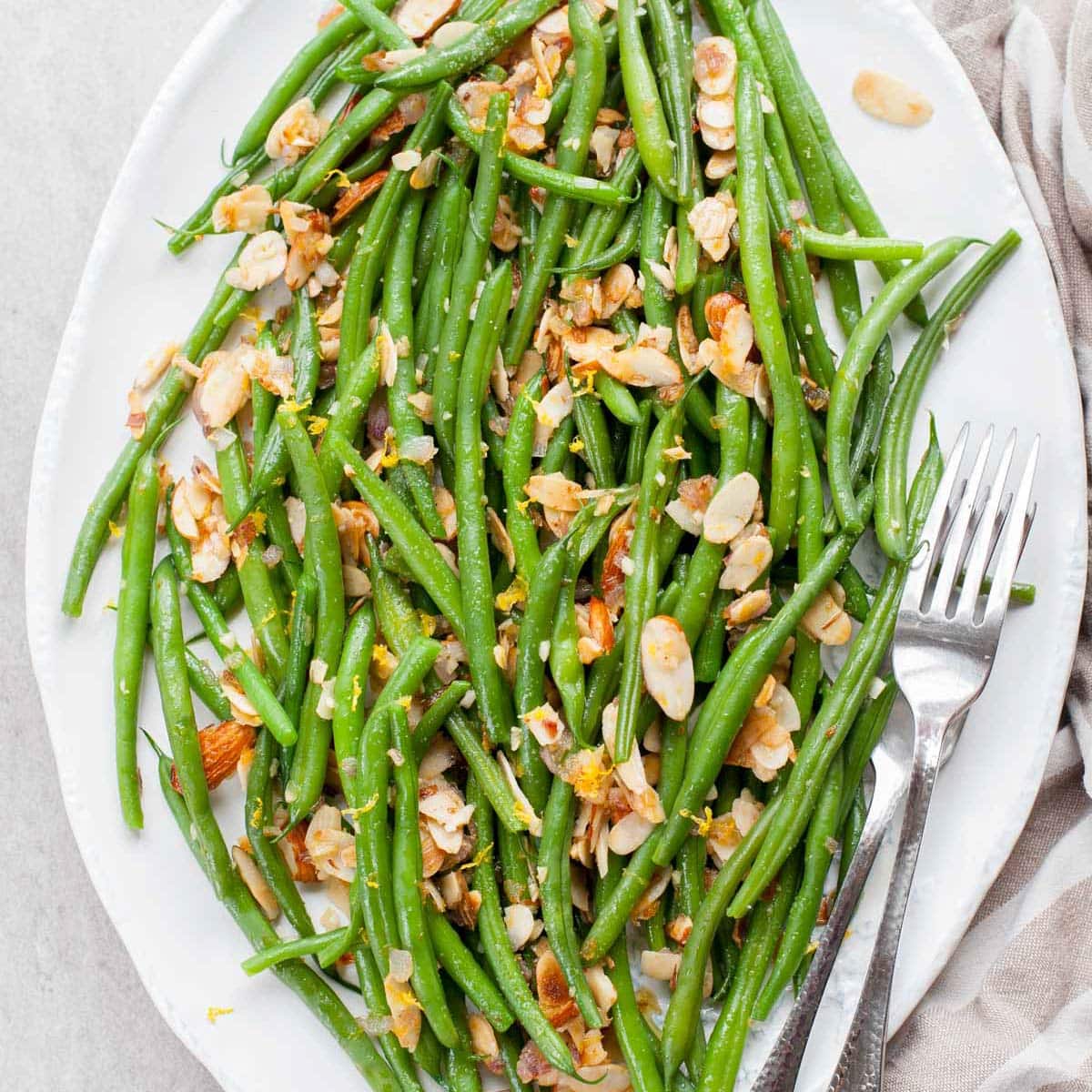 Green beans almondine on a white plate.