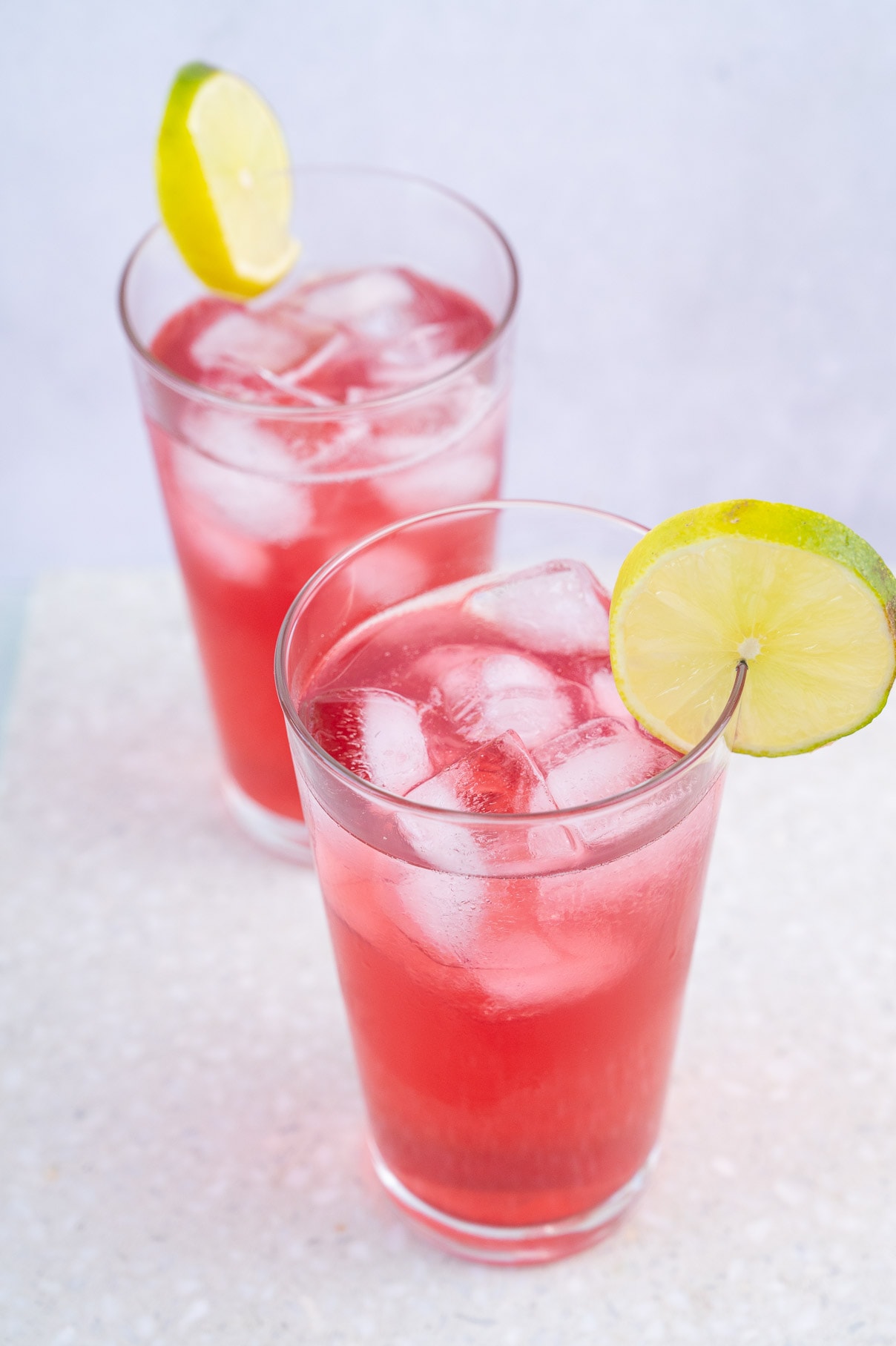 Two glasses with bay breeze drink garnished with lime slices.