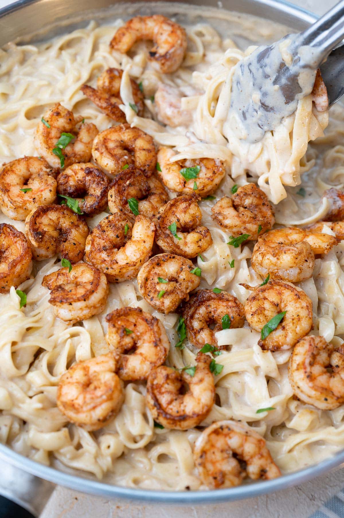 Cajun-spiced shrimp with tagliatelle pasta and alfredo sauce in a pan.