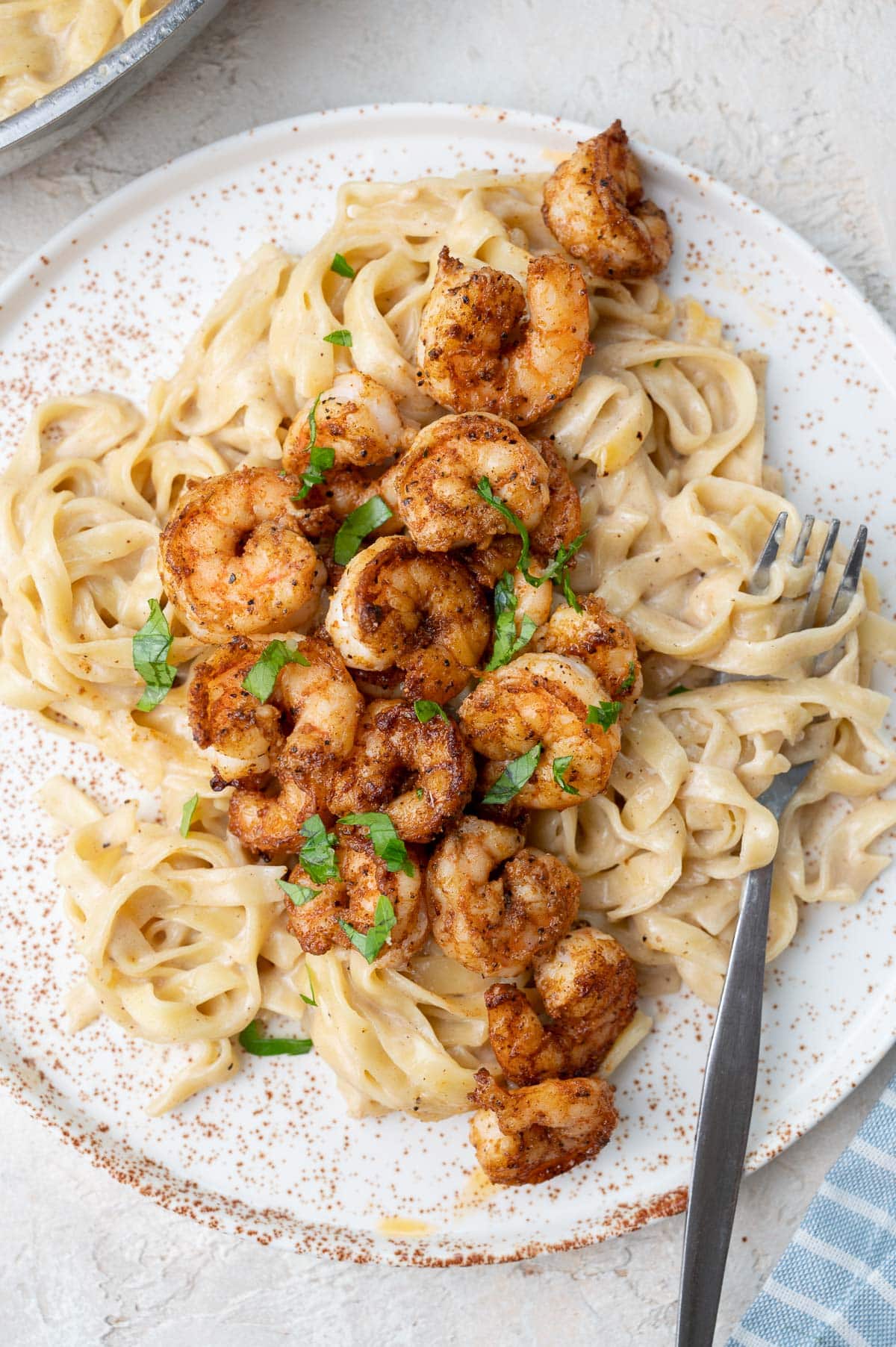 A close up picture of Cajun shrimp pasta on a white plate.