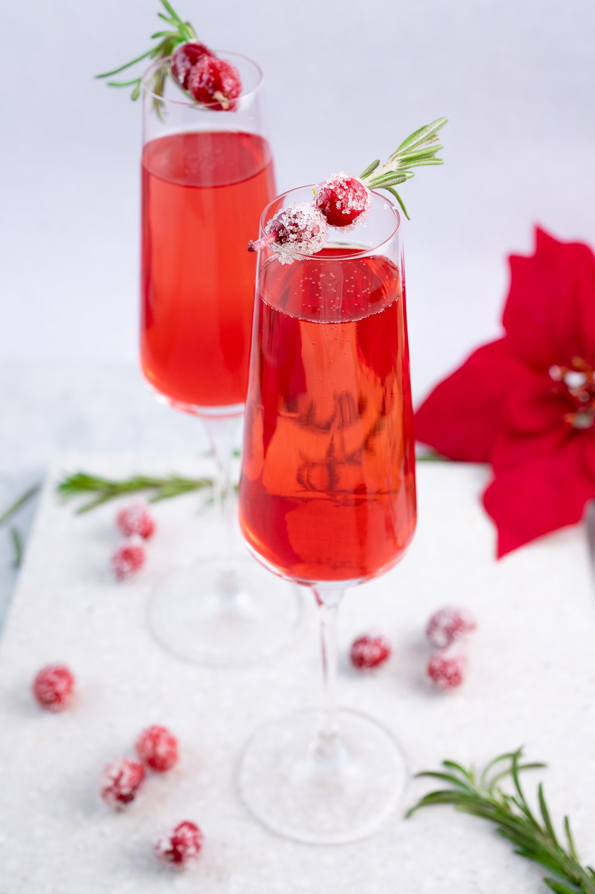 Two glasses with cranberry mimosa decorated with sugared cranberries.