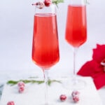Two champagne glasses with cranberry mimosa.
