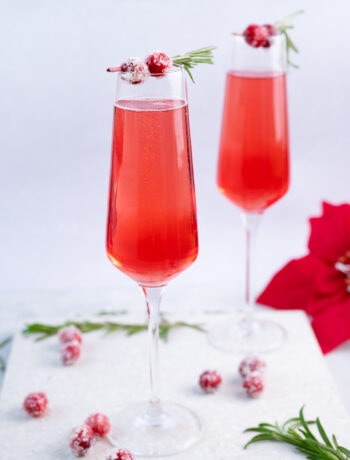 Two champagne glasses with cranberry mimosa.