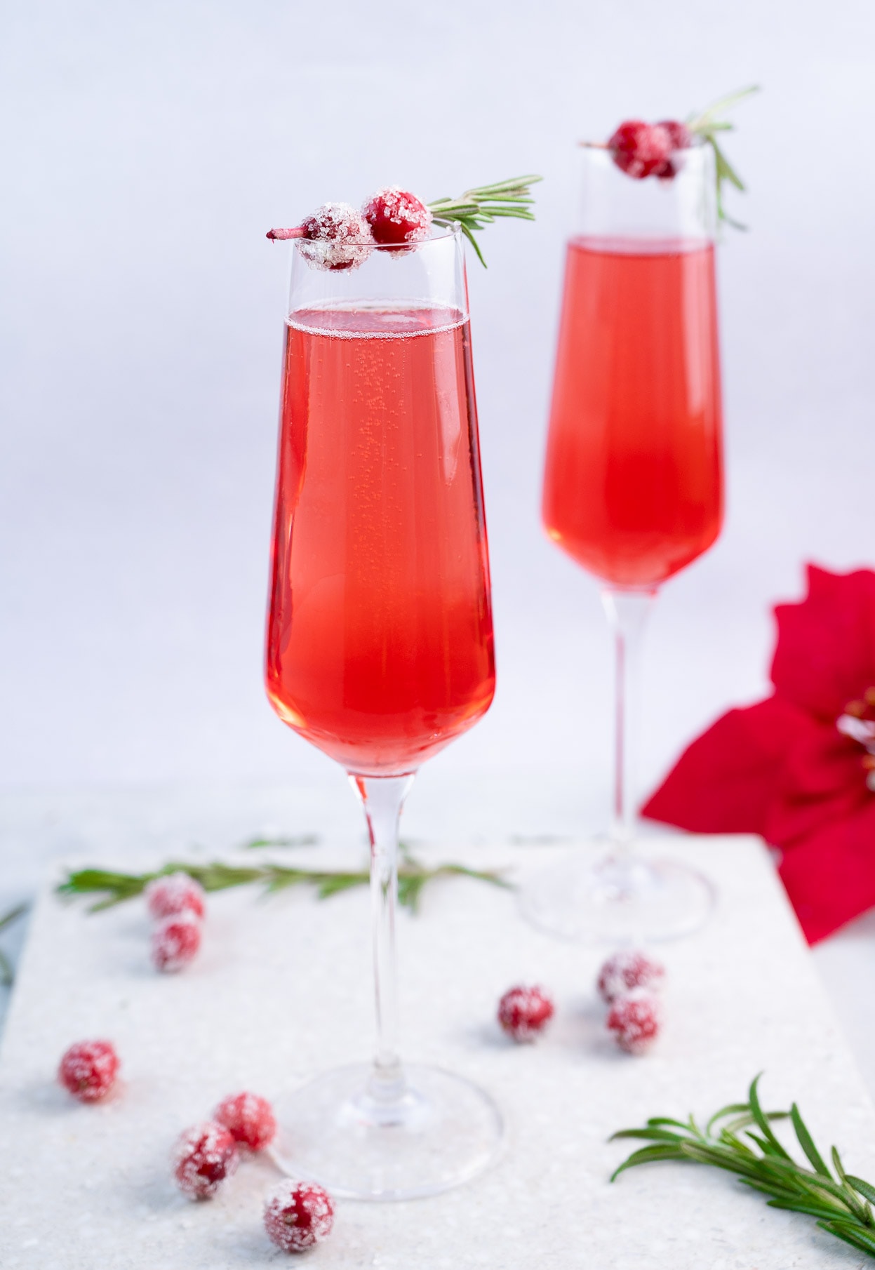 Two glasses with cranberry mimosa decorated with sugared cranberries.