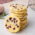 A stack of cranberry shortbread cookies on a grey stone board.