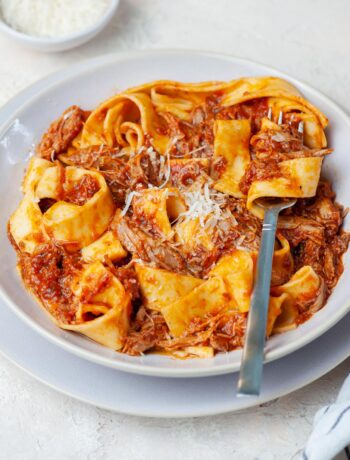 Duck ragu with pappardele pasta in a beige plate.