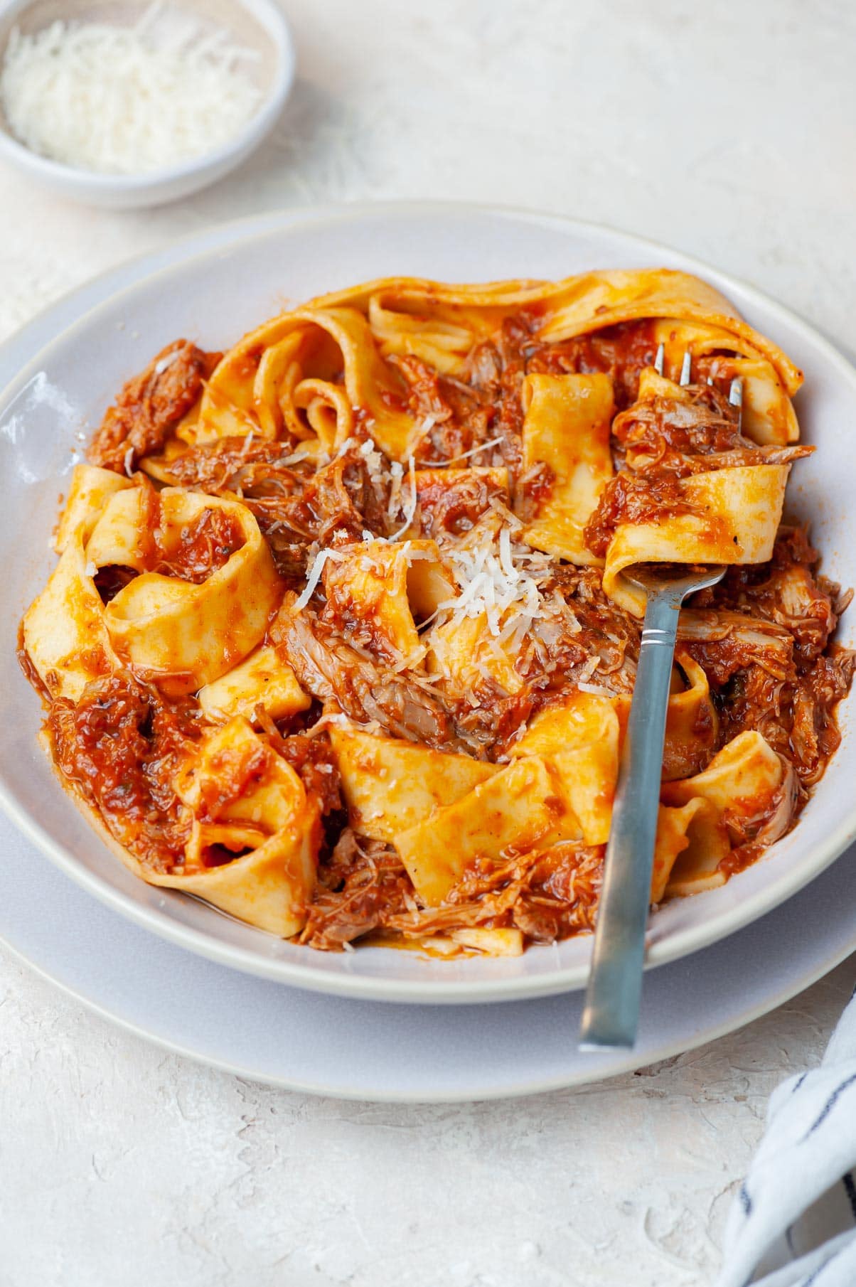 Duck ragu with pappardele pasta in a beige plate.