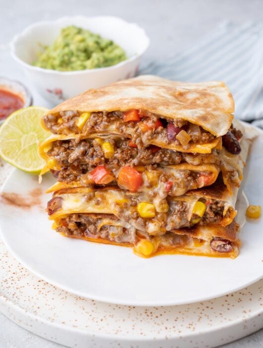 A stack of ground beef quesadillas on a white plate.