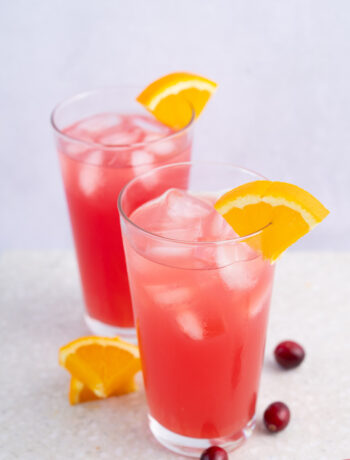 Two glasses with madras drink granished with orange slices.