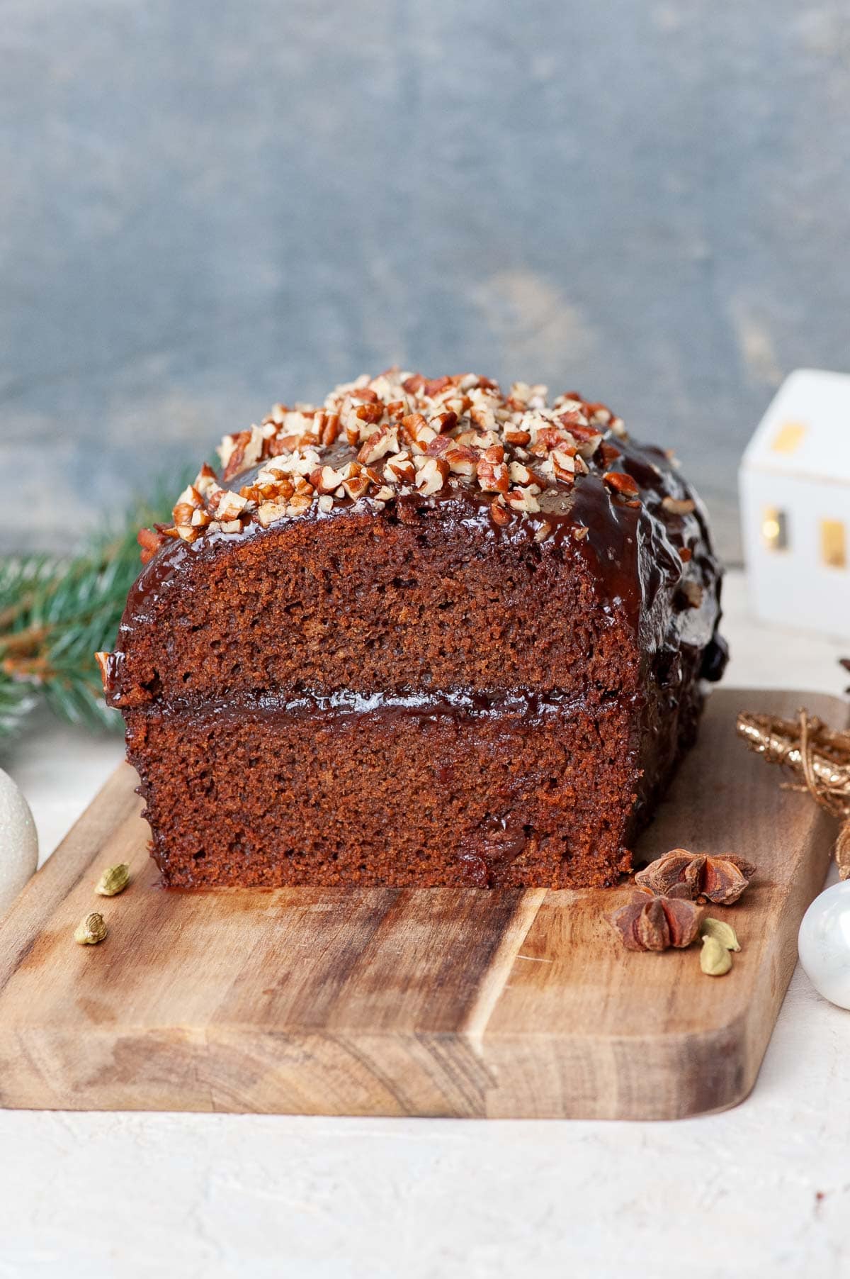 Piernik cake cut in half on a wooden board. Christmas decorations in the background.