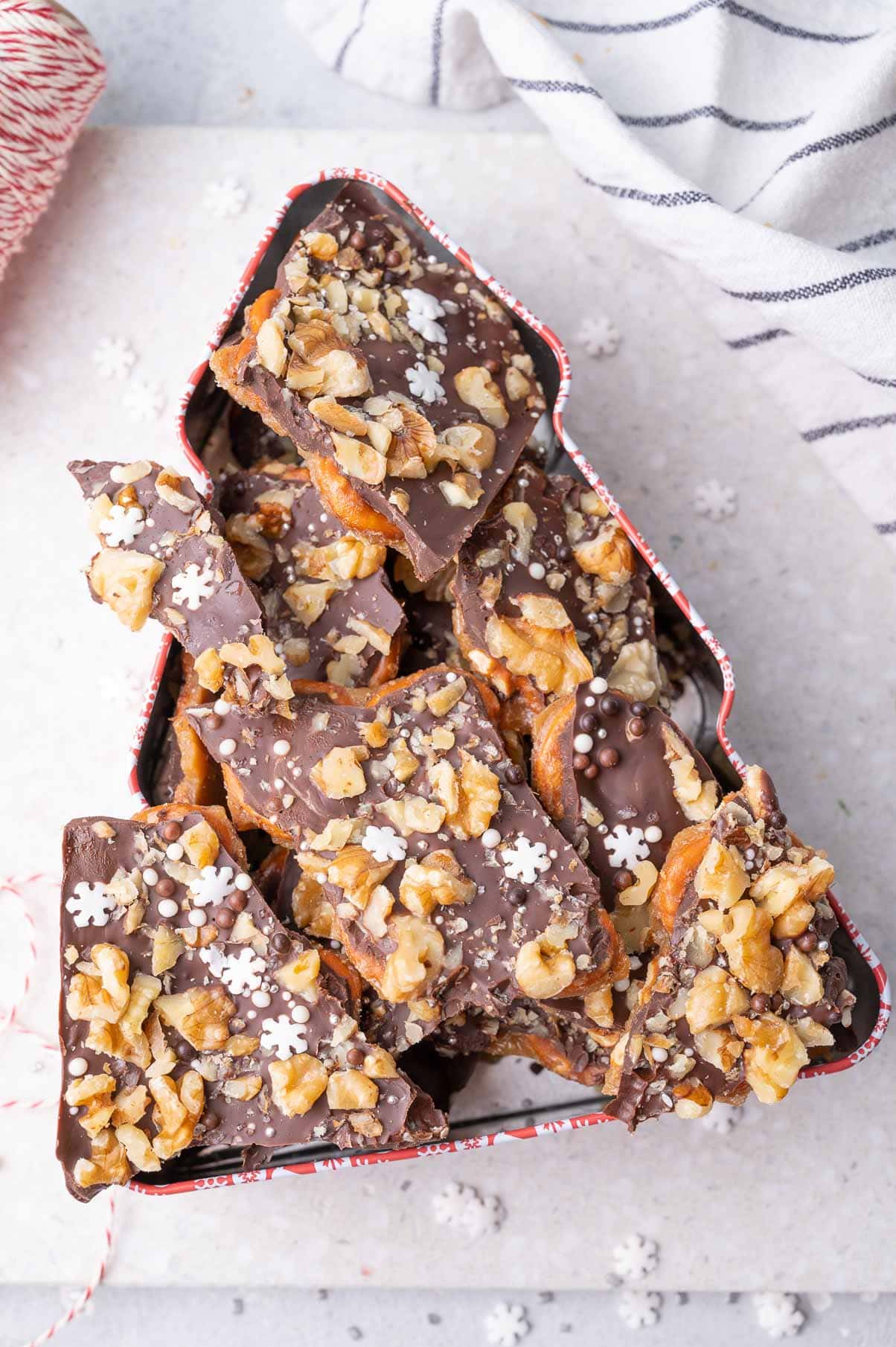 Pretzel toffee with with walnuts in a Christmas tree-shaped cookie tin.