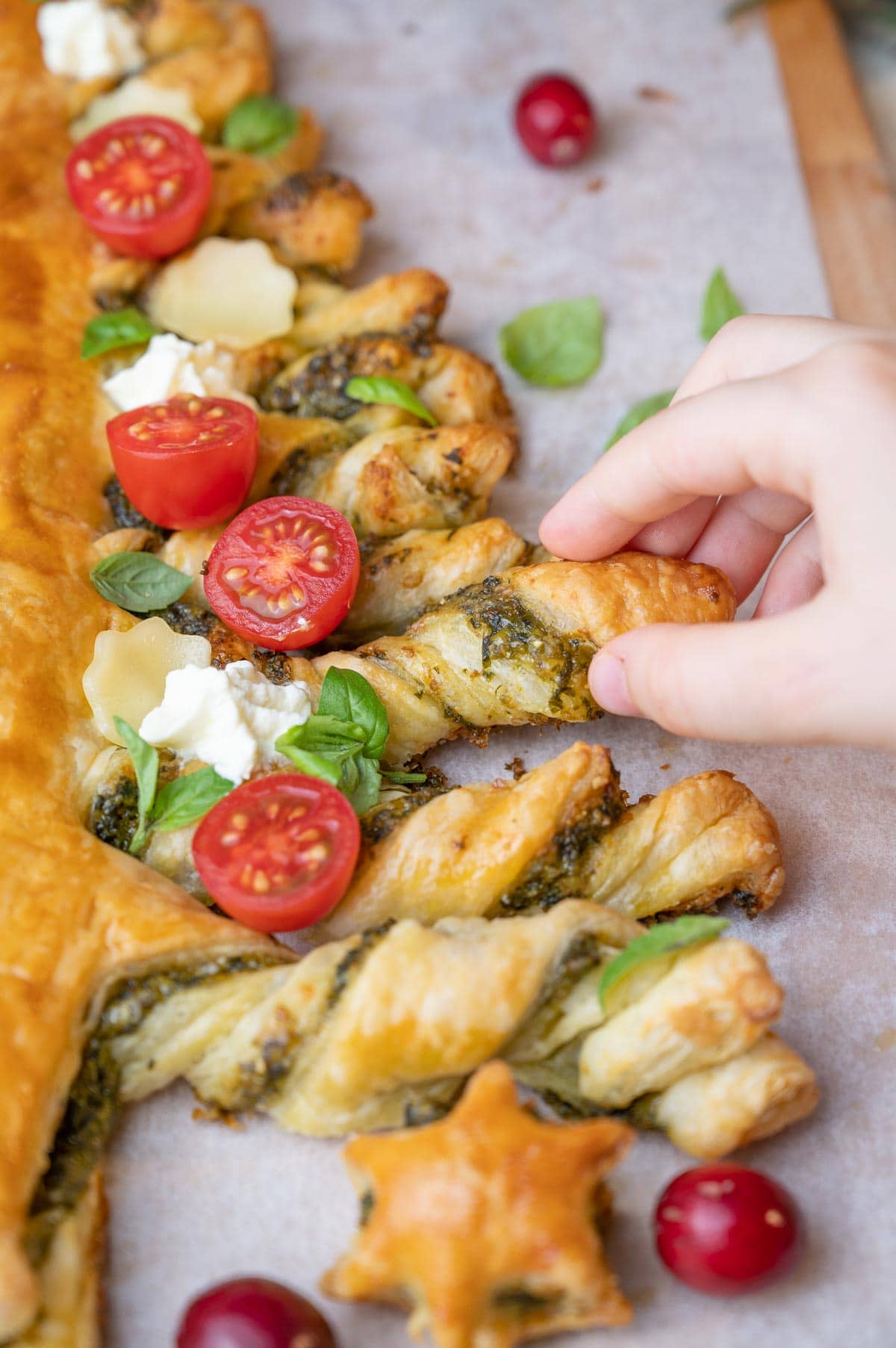 A child's hand is grabbing a piece of puff pastry Christmas tree.