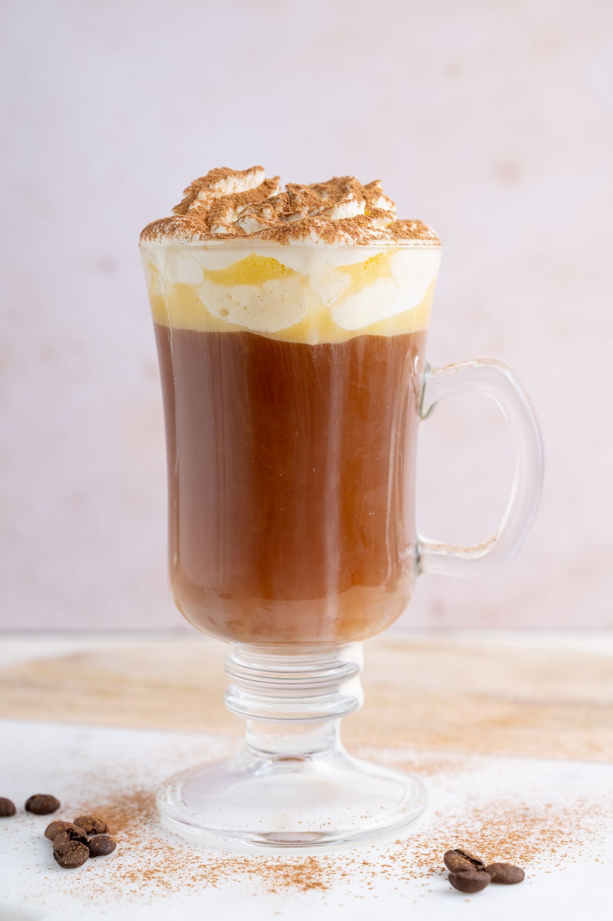 A glass with amaretto coffee topped with whipped cream and cinnamon