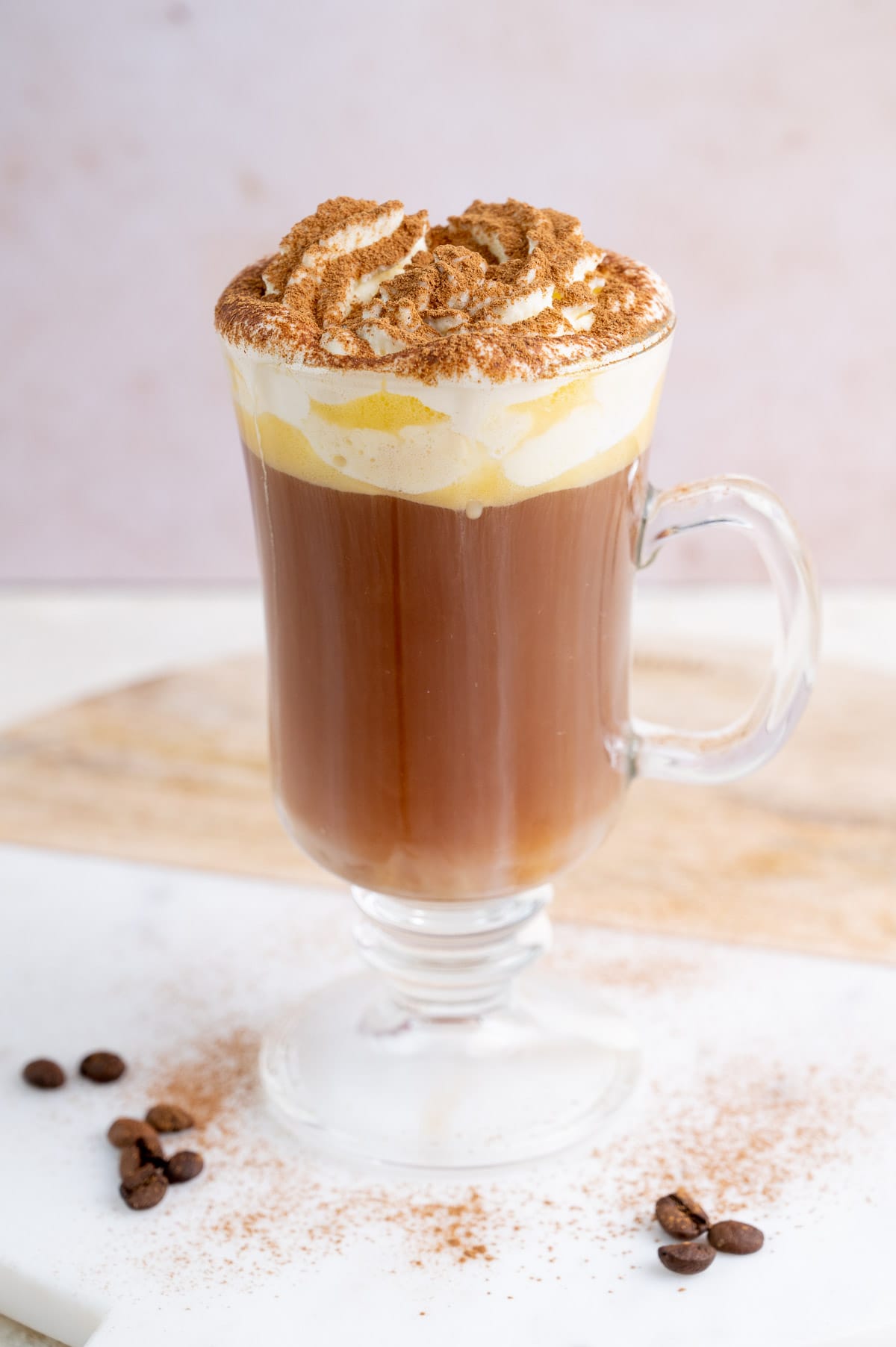 A glass with amaretto coffee topped with whipped cream and cinnamon.