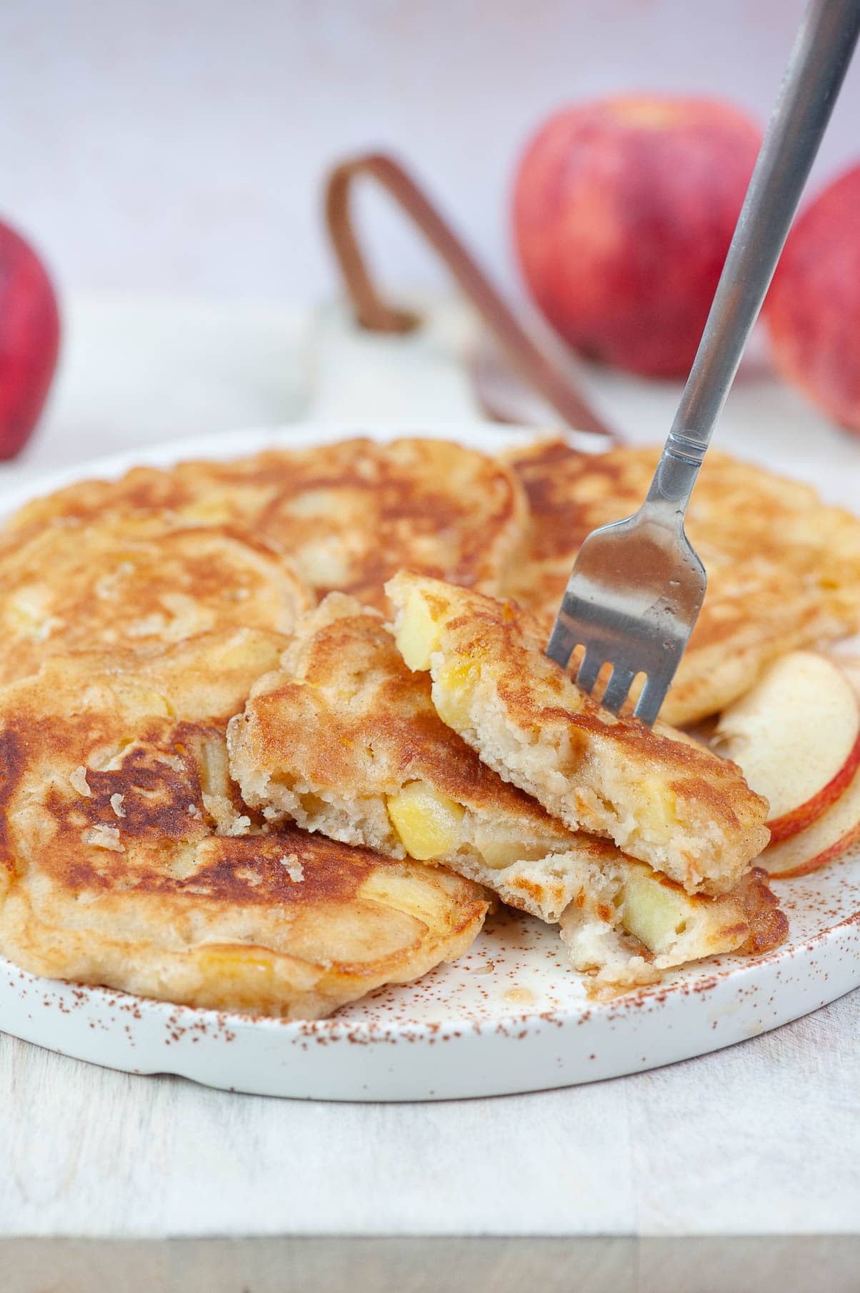 Apple cinnamon pancakes stuck on a fork on a white plate.