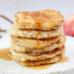 A stack of apple cinnamon pancakes on a white plate.