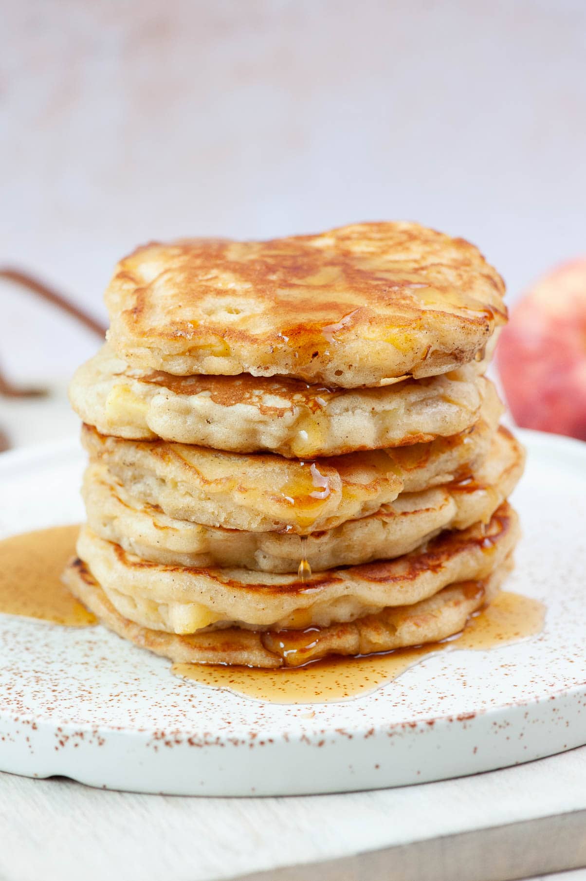 A stack of apple cinnamon pancakes on a white plate.