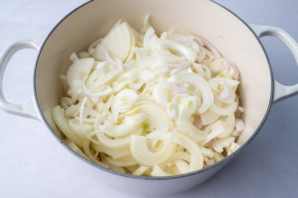 Raw sliced onion in a white pot.