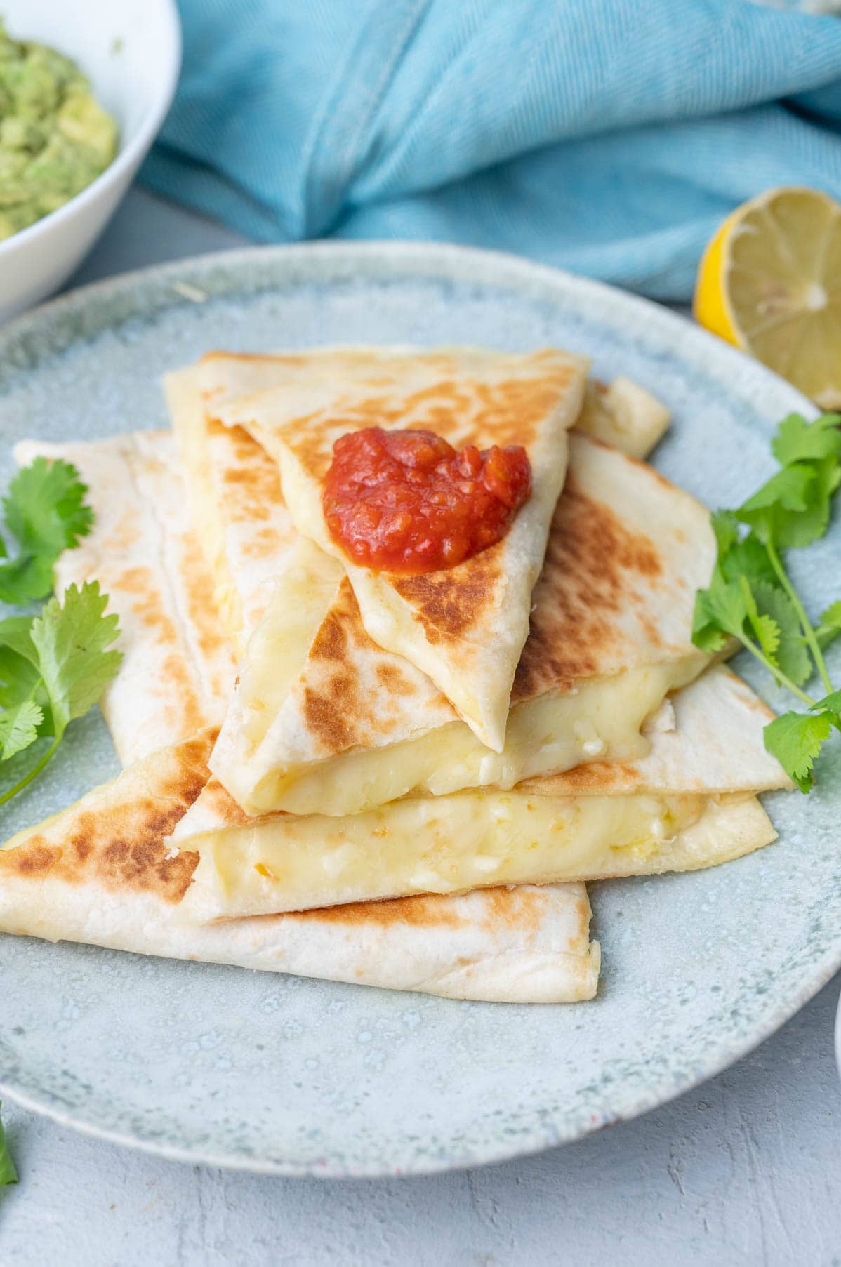Cheese quesadillas cut into triangles on a green plate.