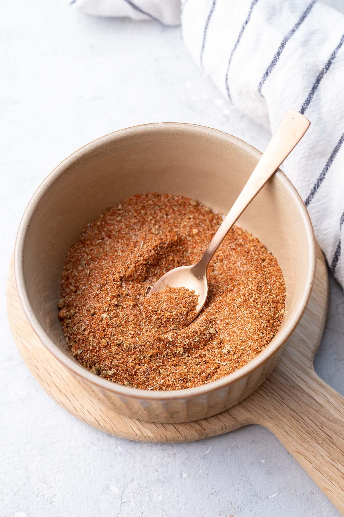 Fajita seasoning in a brown bowl with a gold spoon.