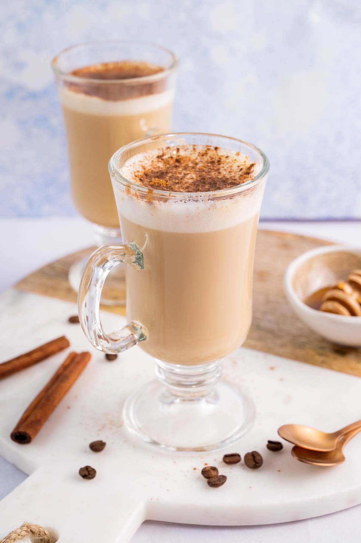 Two glasses with coffee with honey and cinnamon.