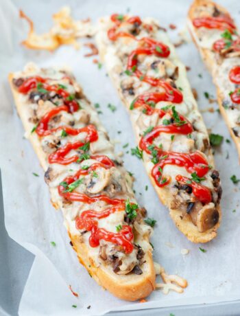 Zapiekanki on a baking sheet lined with parchment paper.