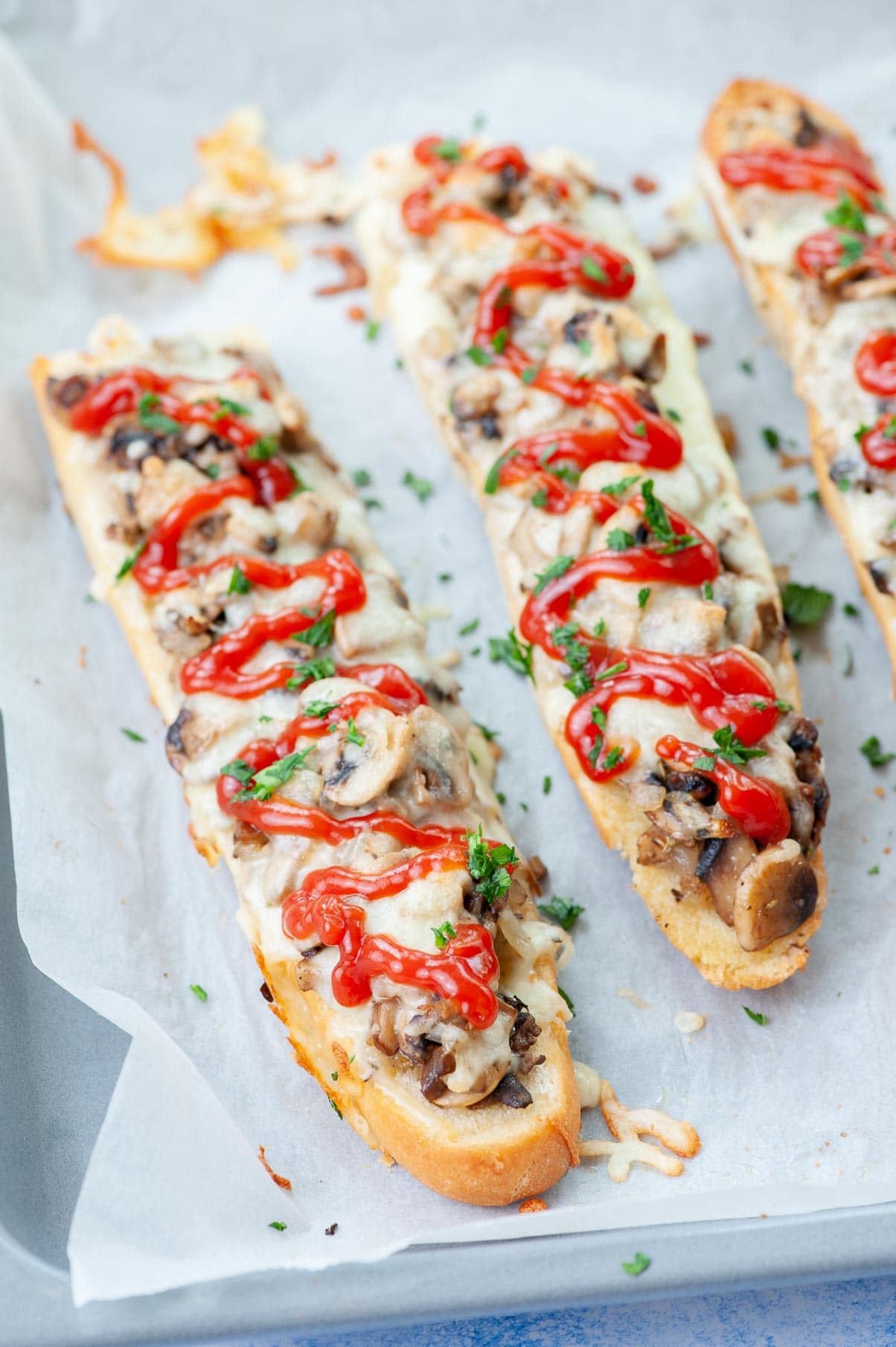 Zapiekanki on a baking sheet lined with parchment paper.