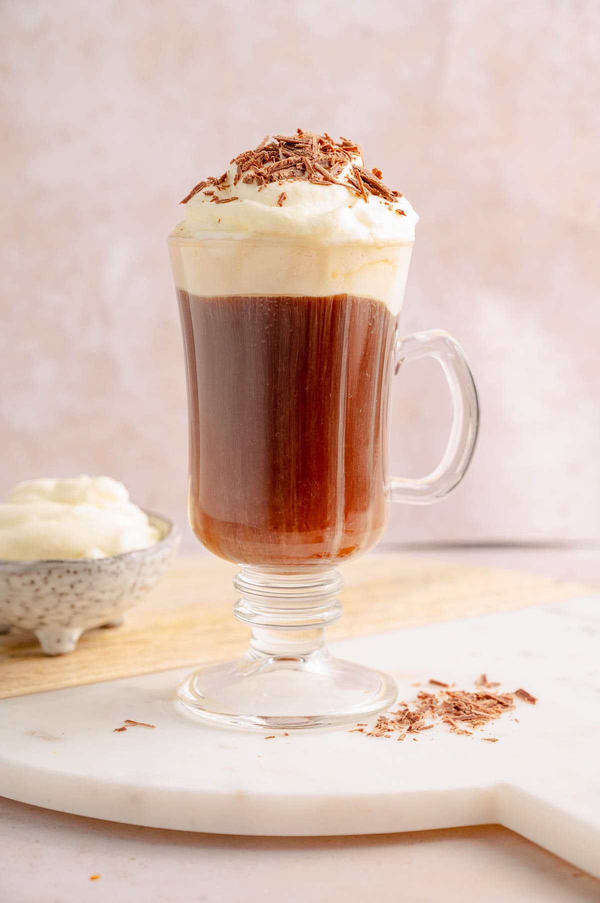 Bourbon coffee with whipped cream in a coffee mug on a white wooden board.