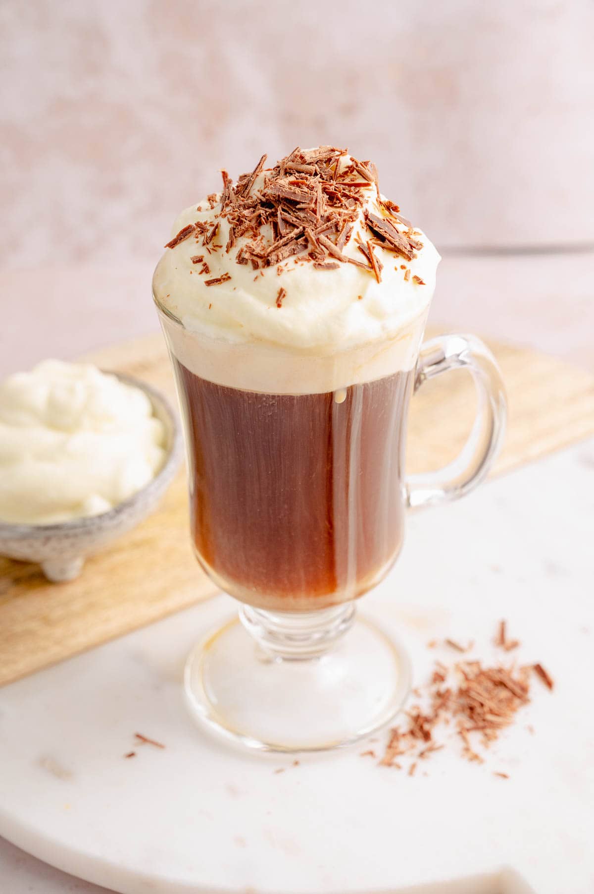 Bourbon coffee with whipped cream in a coffee mug on a white wooden board.