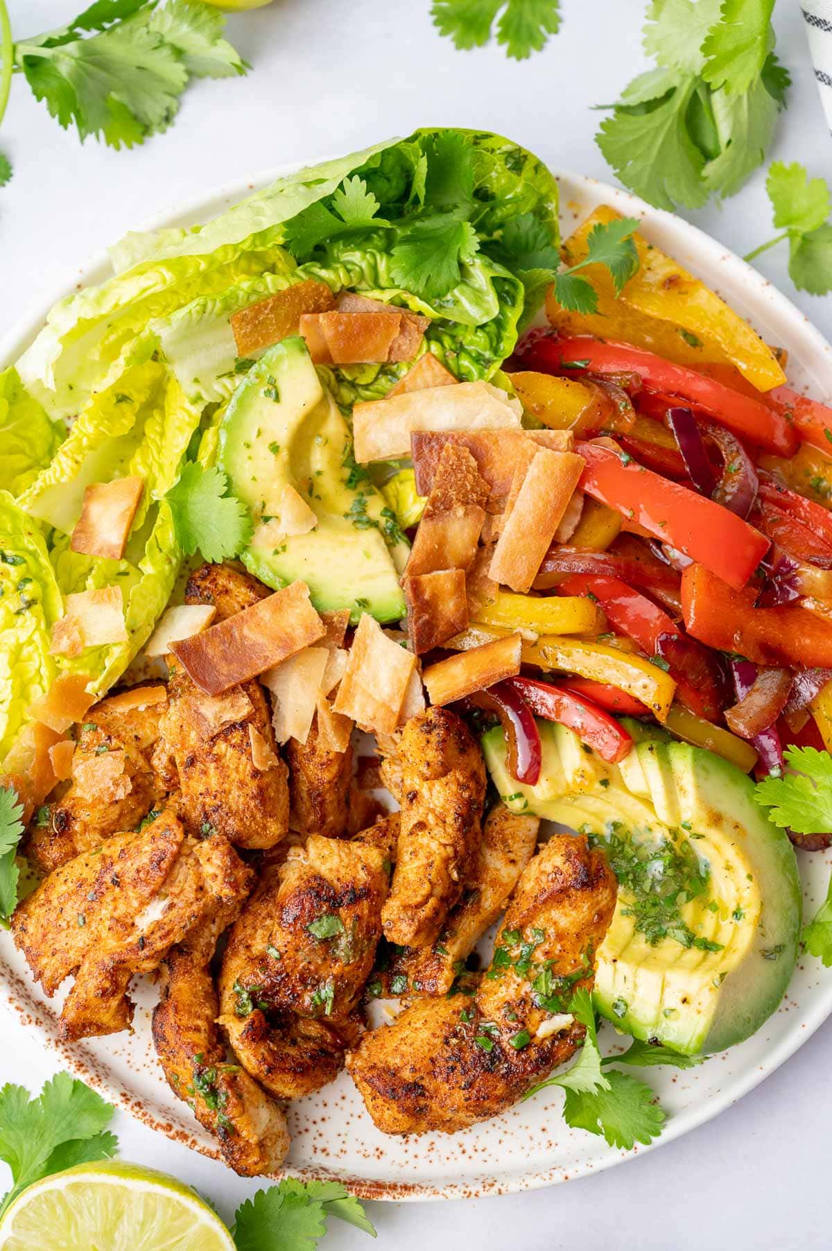 A close up photo of chicken fajita salad on a white plate.