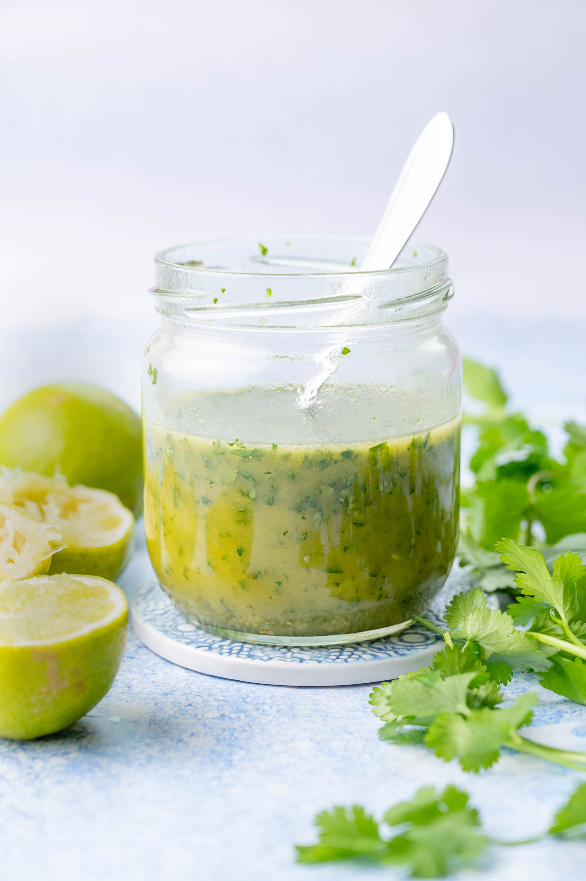 Cilantro lime vinaigrette in a jar. Limes and cilantro in the background.