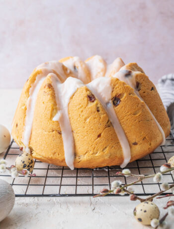 Polish Easter babka glazed with icing on a black cooling rack.