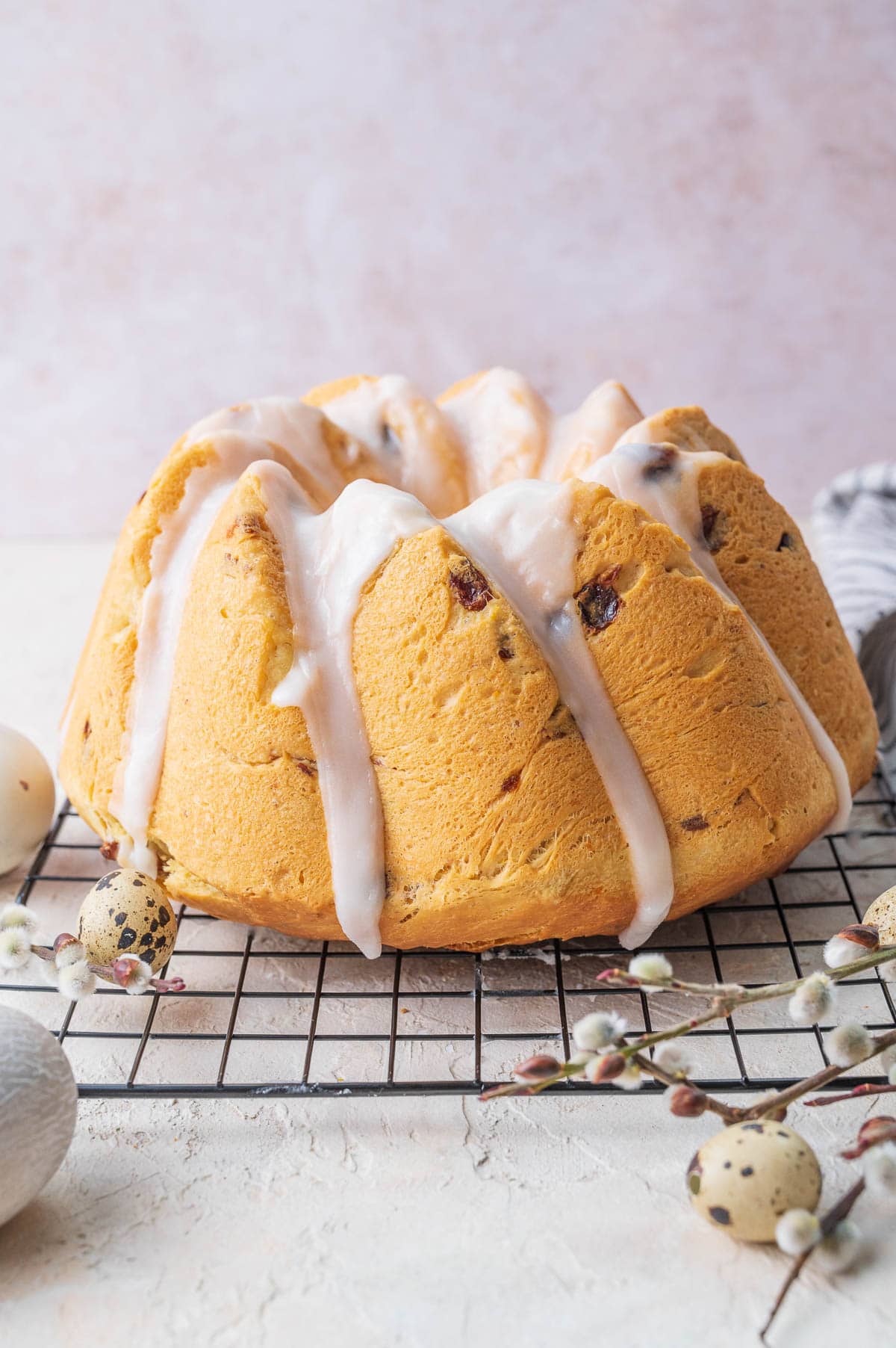 Yeast raisin babka glazed with icing on a cooling rack.