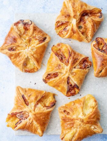 Ham and cheese puff pastry appetizers on a grey stone board.