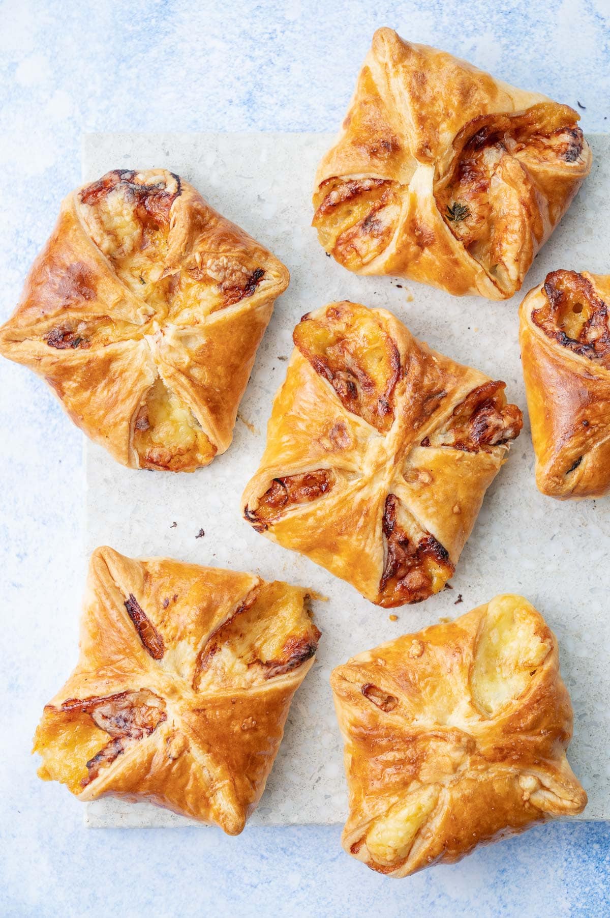 Ham and cheese puff pastry appetizers on a grey stone board.