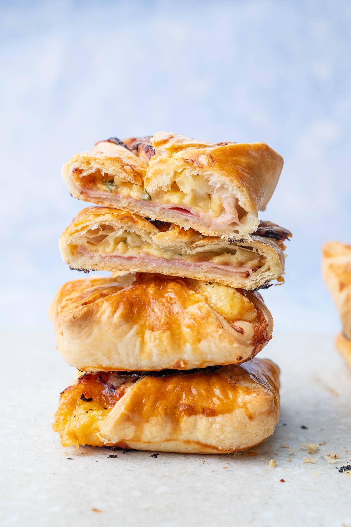 A stack of puff pastry pastried with ham and cheese on a grey stone board.