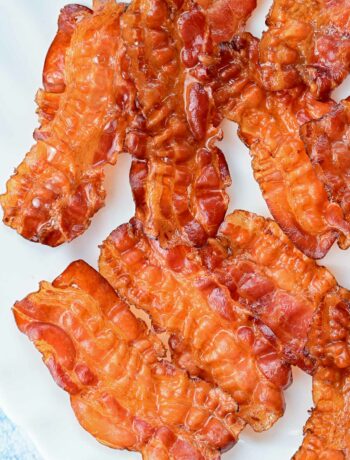 Baked bacon slices on a white plate.