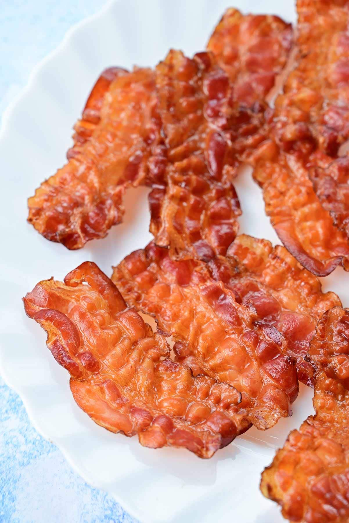 Baked bacon slices on a white plate.