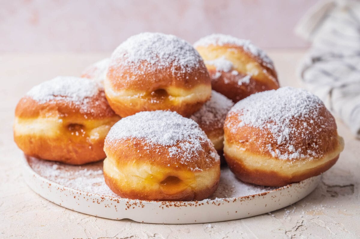Krapfen dusted with powdered sugar on a white plate.