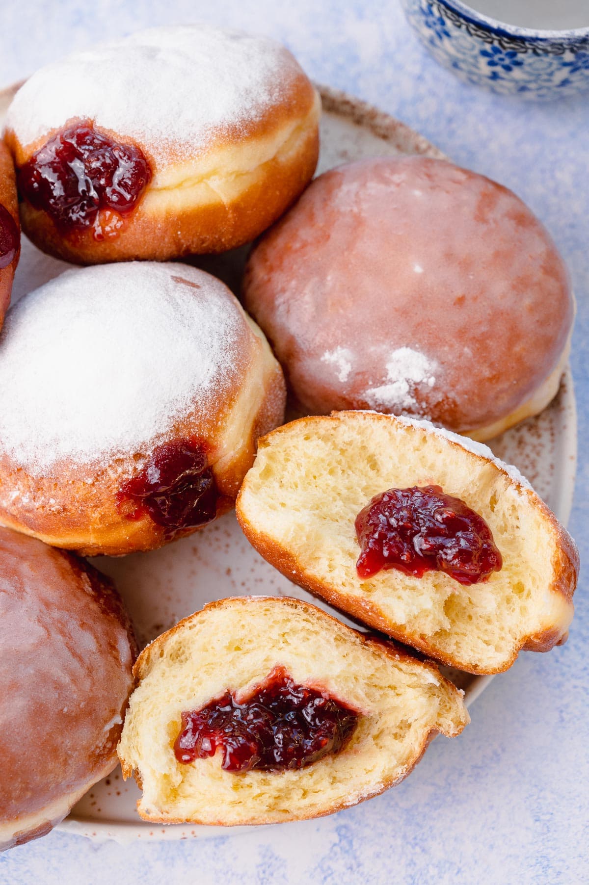 Paczki on a white plate on a blue background.